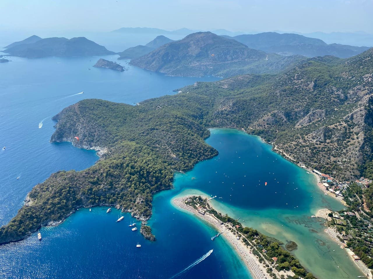 The Ölüdeniz lagoon seen from the air, with paragliders over the coastline.